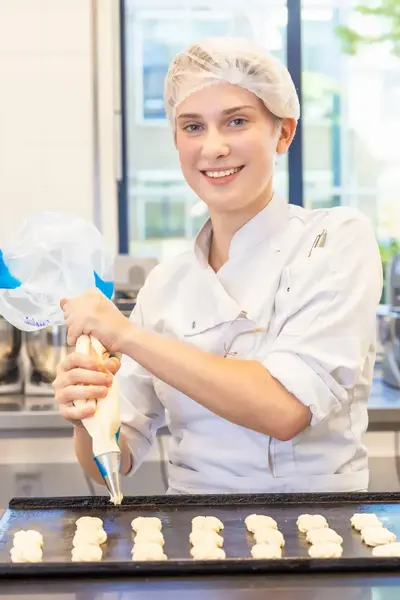 Banketbakker spuit deeg uit spuitzak op bakplaat