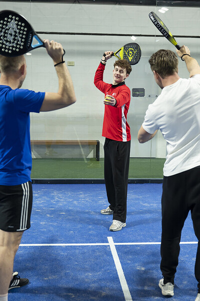 Jongen staat aan het net en slaat een bal.