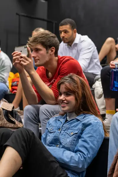 Studenten in een theaterzaal kijken aandachtig en lachen tijdens een tentoonstelling.