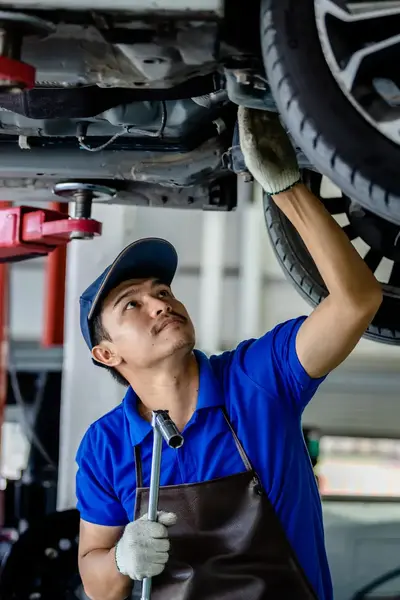 Student werkt onder auto op reparatiebrug