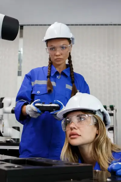 Studenten in overall met veiligheidsbril inspecteren machine.