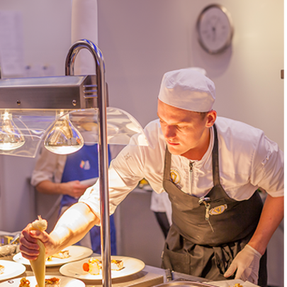 Student in kokskleding oefent basistechnieken in een professionele horecakeuken