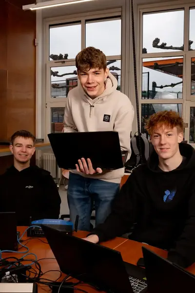 Vier studenten werken samen aan een game op hun laptops in een klaslokaal.