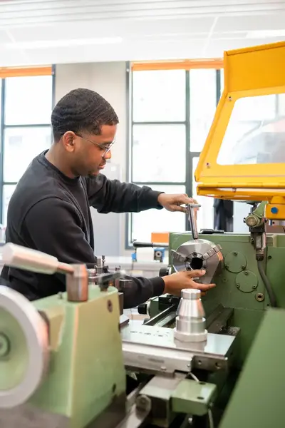 Student sleutelt aan machine in praktijklokaal.