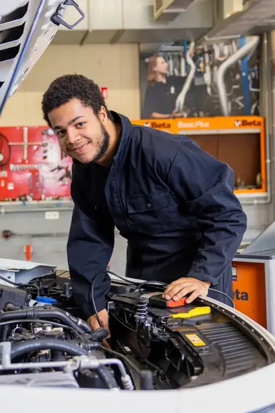 Student sleutelt onder motorkap auto in garage.