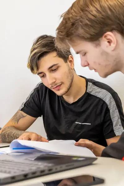 Twee studenten werken samen aan een opdracht achter een laptop