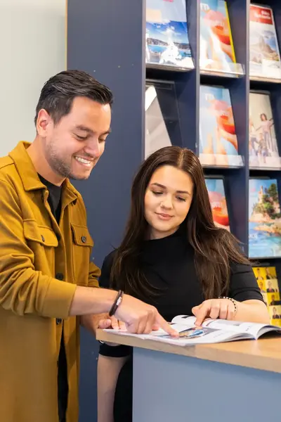 Studenten Toerisme en Recreatie bekijken vakantiefolder temidden van vakantiefolders.