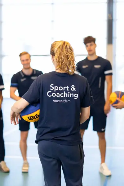 Studenten in sportzaal met ballen in de hand