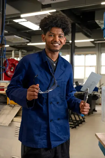 Student in blauw werkpak in een fabrieksomgeving