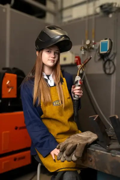 Student in werkkleding met lasapparaat in werkplaats