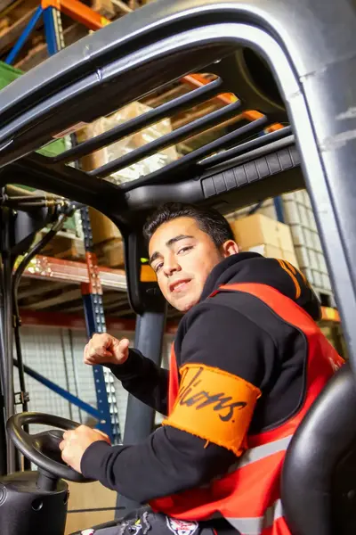 Jongen in vorkheftruck aan het werk in een magazijn.